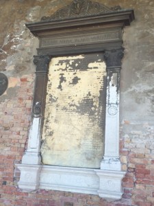 The fading war memorial, among the many tablets set on the side wall under the portico.