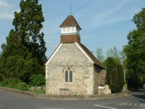 St Andrew's church, with the rectory just visible on the right. Since 1933, the little window has contained glass portraits of Herbert (on the right, with his viol) and Ferrar. 