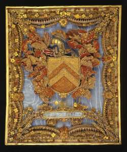 The coat-of-arms of the Rev. Thomas Whitehurst. (Credit: The Fitzwilliam Museum) Picture worked in rolled paper (red, blue and white with gilt edges), in the centre of which are the arms of the Rev. Thomas Whitehurst surrounded with foliage and flowers on a light blue grosgrain background. Below are the initials TW and the date 1699. Light blue grosgrain background probably added in the early 19th century. Framed in 1832. C.1699