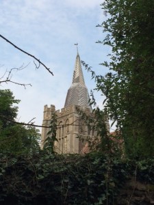 The tower and twisted spire from over the churchyard wall.